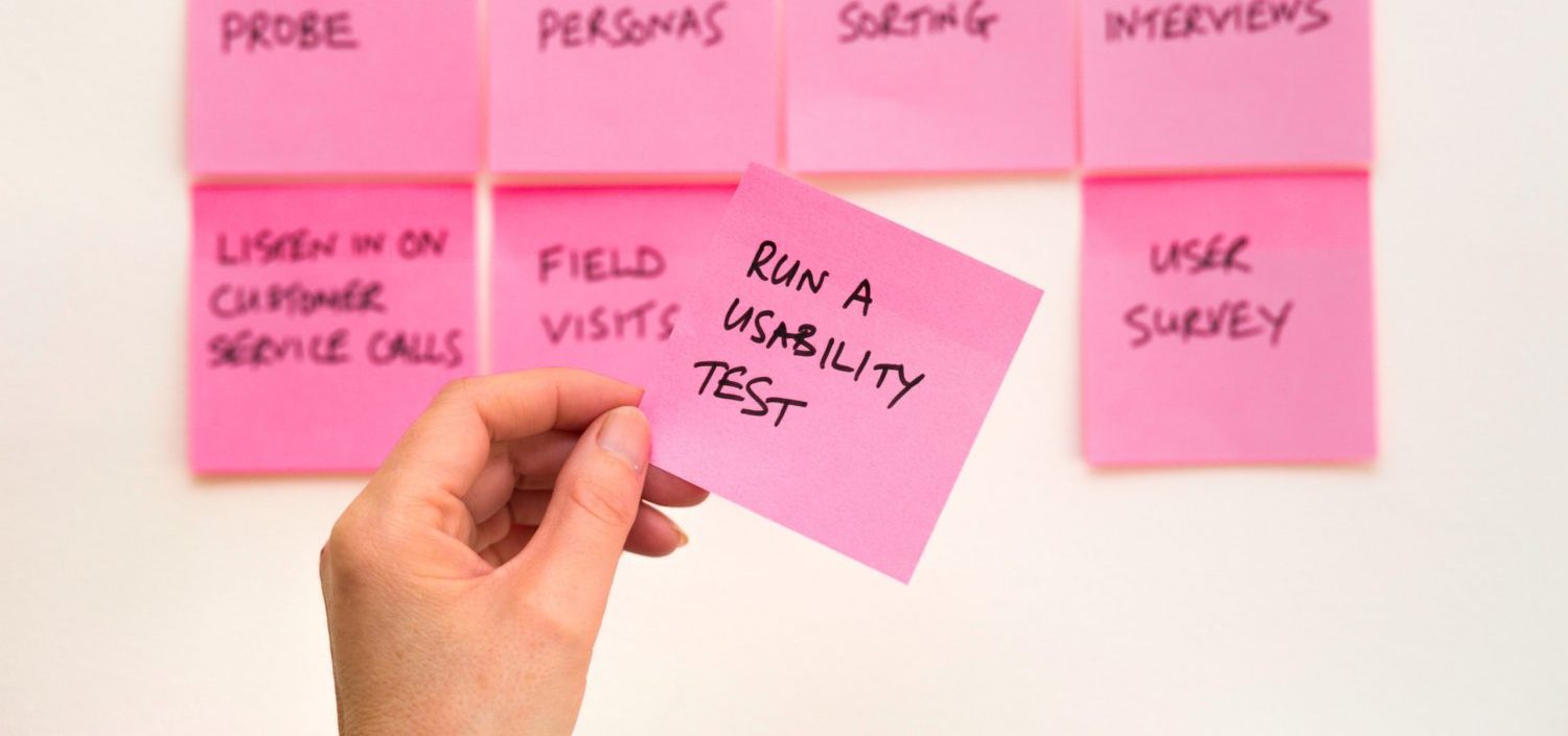 Person holding pink sticky notes with research tasks
